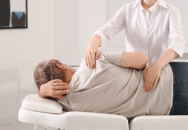 Mujer dando un masaje traumatológico a un señor